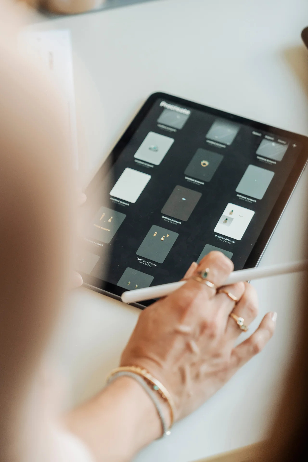 Mão de fundadora Raris desenhando peças de alta joalheria em Procreate, anéis e bracelete em ouro com esmeraldas