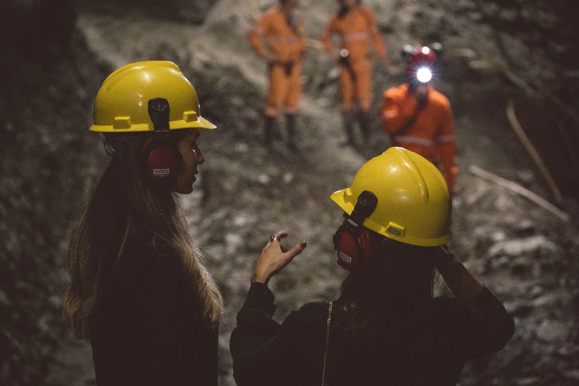 Mineração subterrânea Belmont em Itabira, Minas Gerais — capacetes amarelos iluminados por lanternas no túnel da mina